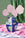 The Claire Johnson Paper Vase by Octaevo in blue, with abstract art, holds pink flowers on satin background. 