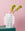 Two yellow-green flowers in an OCTAEVO Coral Paper Vase set against a pink background and green surface.