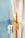 Two twisted candles in Octaevos Flora Candle Holders on a mirrored surface with a pastel blue and cream backdrop.