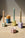 Four Octaevo Flora Candle Holders with taper candles arranged uniquely, sunlight casting soft shadows.