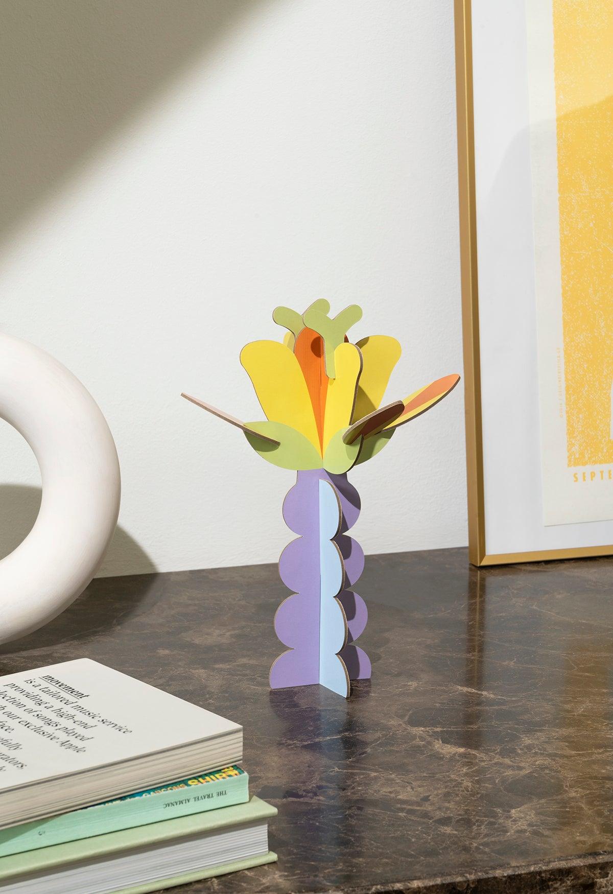 Octaevos Flower Paper Sculpture 3 adds a colorful 3D touch to modern decor beside books and framed art.