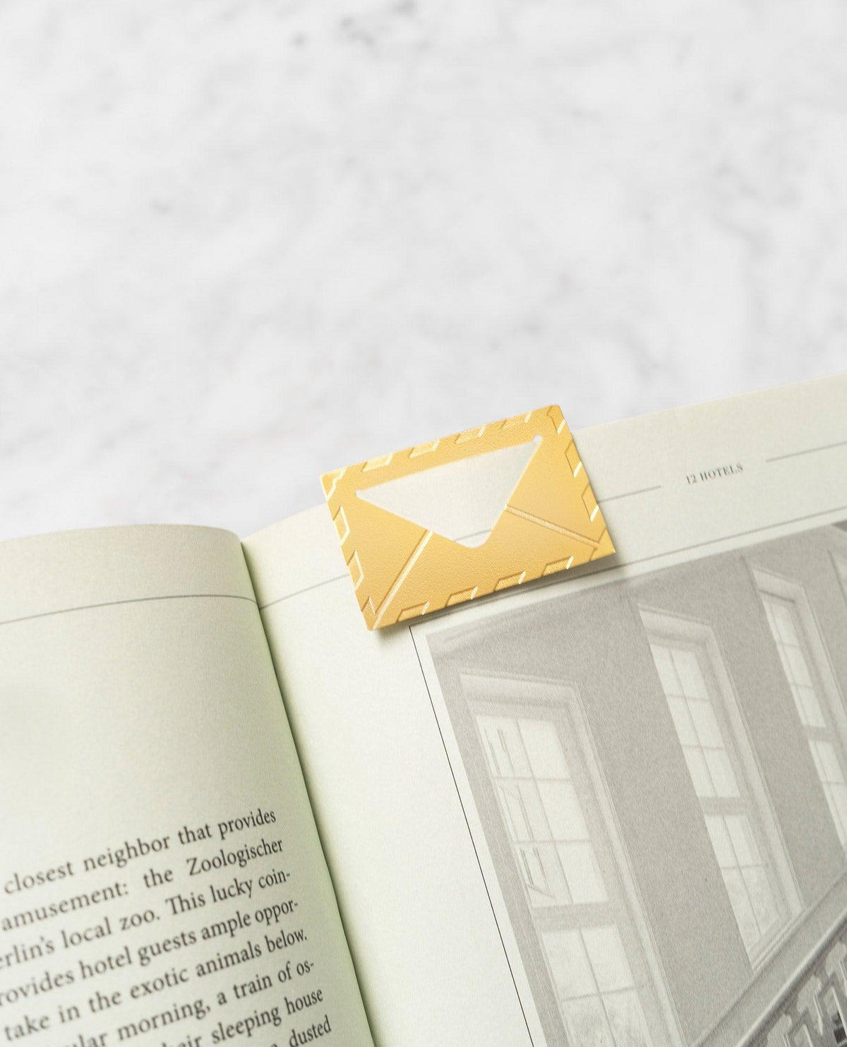 The OCTAEVO Greeting Card Airmail, a stylish yellow envelope bookmark, clips the corner of an open book.