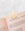 Gold, lips-shaped metal clip bookmark on pink book beside OCTAEVO Greeting Card Kiss, on a marble surface.