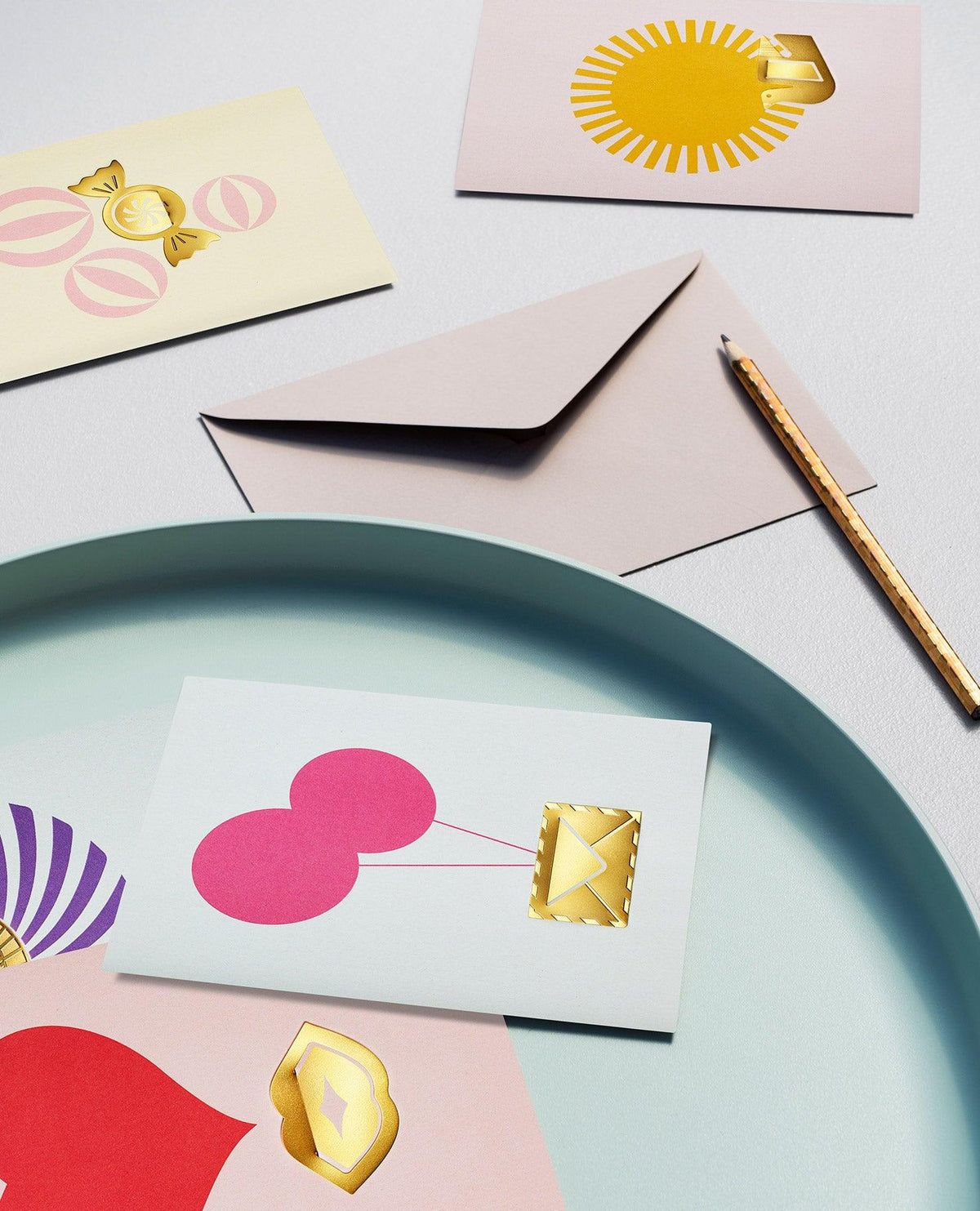 OCTAEVO's Sun Greeting Card, plus gold-foil note cards, a pencil, and clip are displayed on a blue tray.