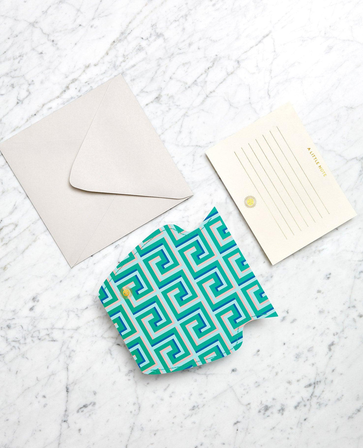 Flat lay of a blank invitation card, envelopes, and the green OCTAEVO Icarus Mini Paper Vase on marble.