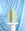 The Icarus Paper Vase by OCTAEVO, with a yellow and blue geometric design, stands against light blue draped fabric.