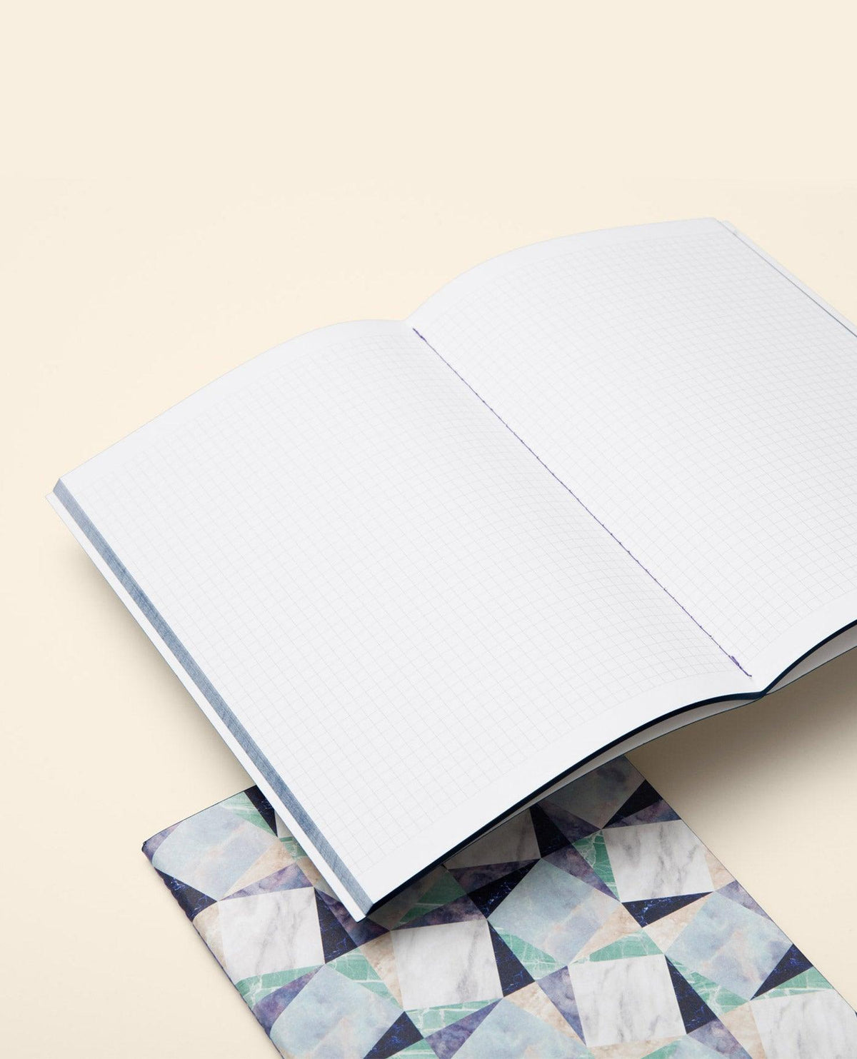 OCTAEVO Marble Notes blue notebook with a geometric cover, open on a light beige surface.