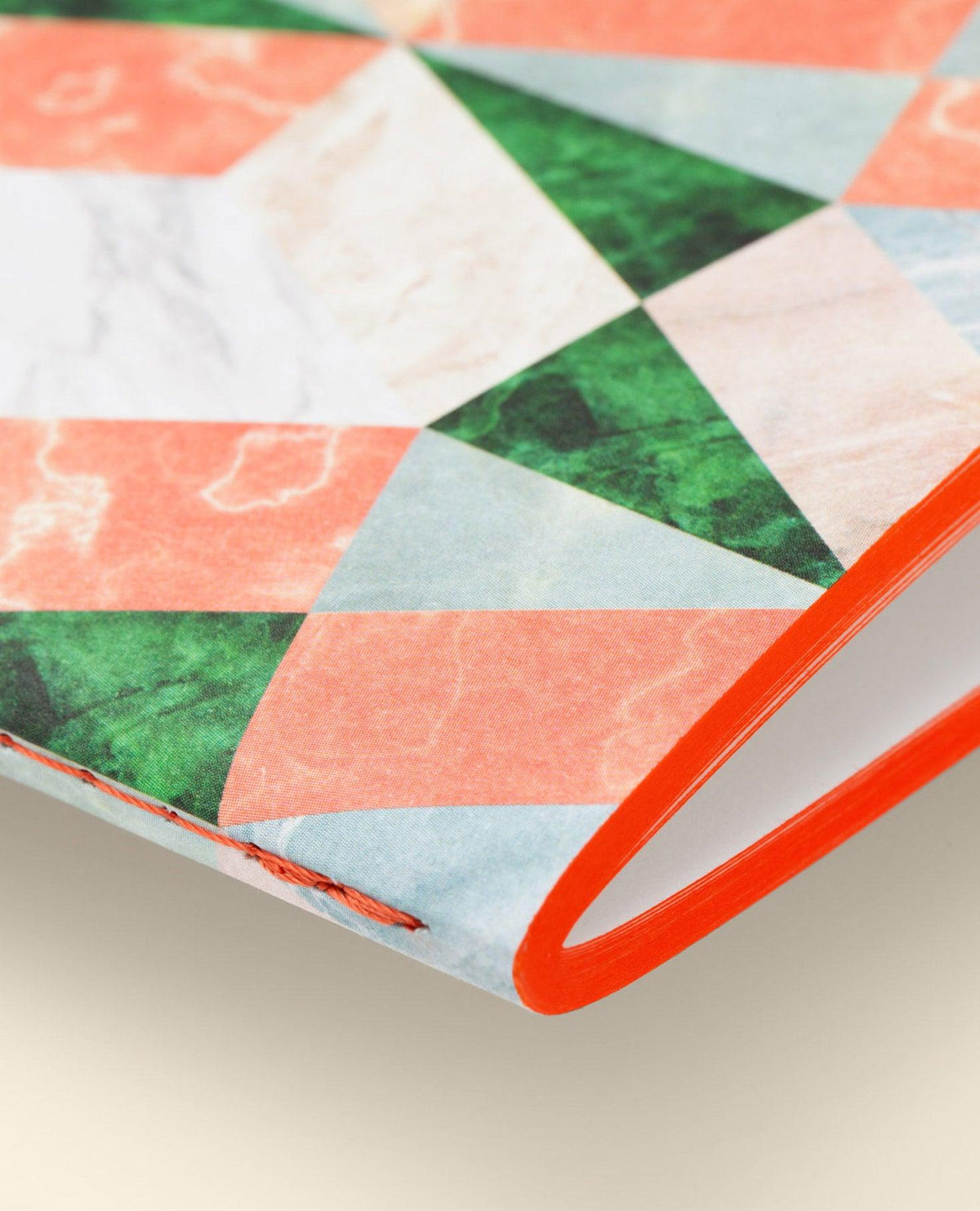 Close-up of OCTAEVOs Marble Notes, an artisan notebook with a marble-pattern cover and red-edged hand-sewn spine.