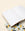 An open, hand-sewn Marble Notes notebook rests atop another one, featuring a geometric yellow and black cover. 