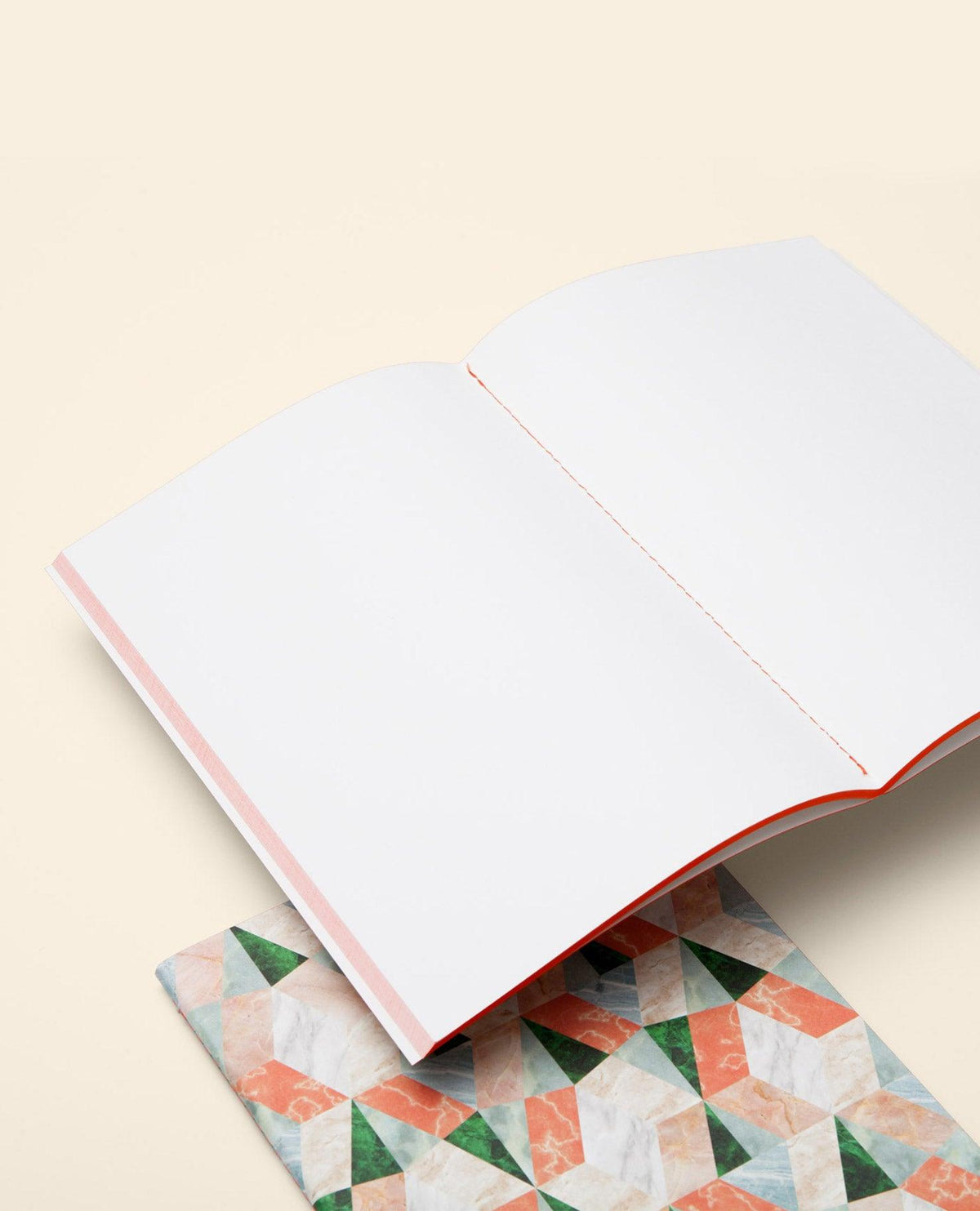 An open red Marble Notes artisan notebook by OCTAEVO with a colorful cover rests on a surface.