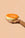 A hand holds the Octaevo Melon Candle—half cantaloupe with a wick—against a peach tabletop backdrop.