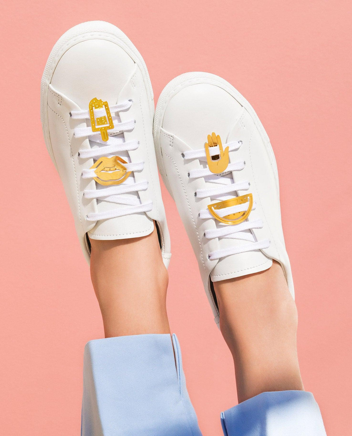 Le Club Metallclips von OCTAEVO: goldene Schnürsenkel-Anhänger in Form von Lippen, Hand, Eis am Stiel & Lächeln bringen Riviera-Flair an weiße Sneaker.