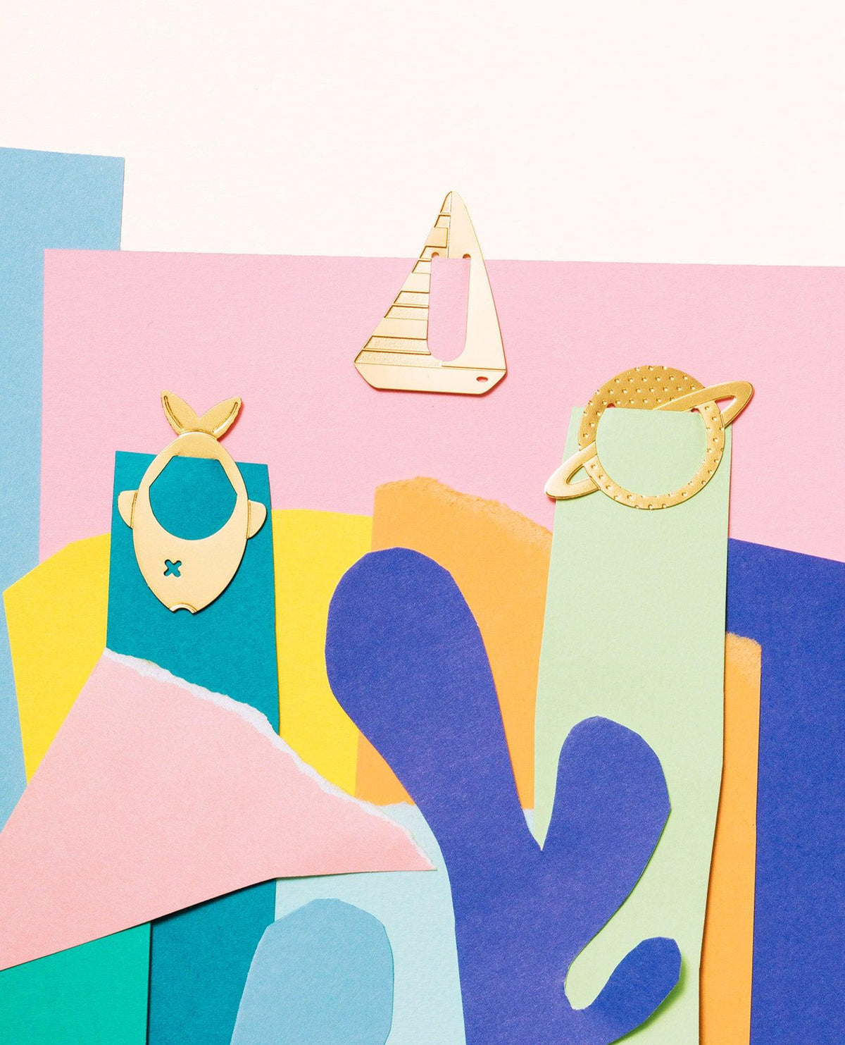 Clips métalliques Navigator par OCTAEVO : des formes de poisson, de bateau et de planète présentées sur des formes en papier déchiré et découpé aux couleurs vives.