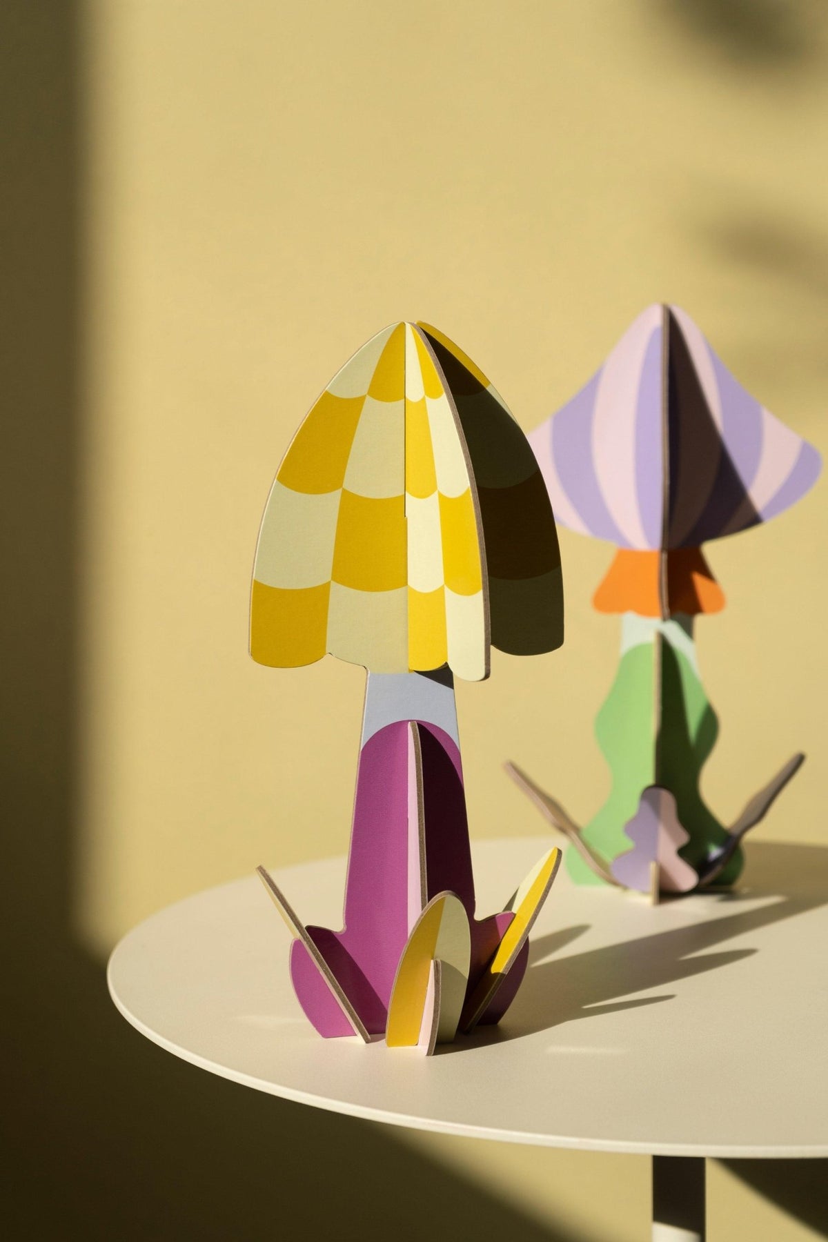 Octaevos Mushroom Paper Sculpture 1, a colorful geometric 3D art piece, sits on a round white dining table.
