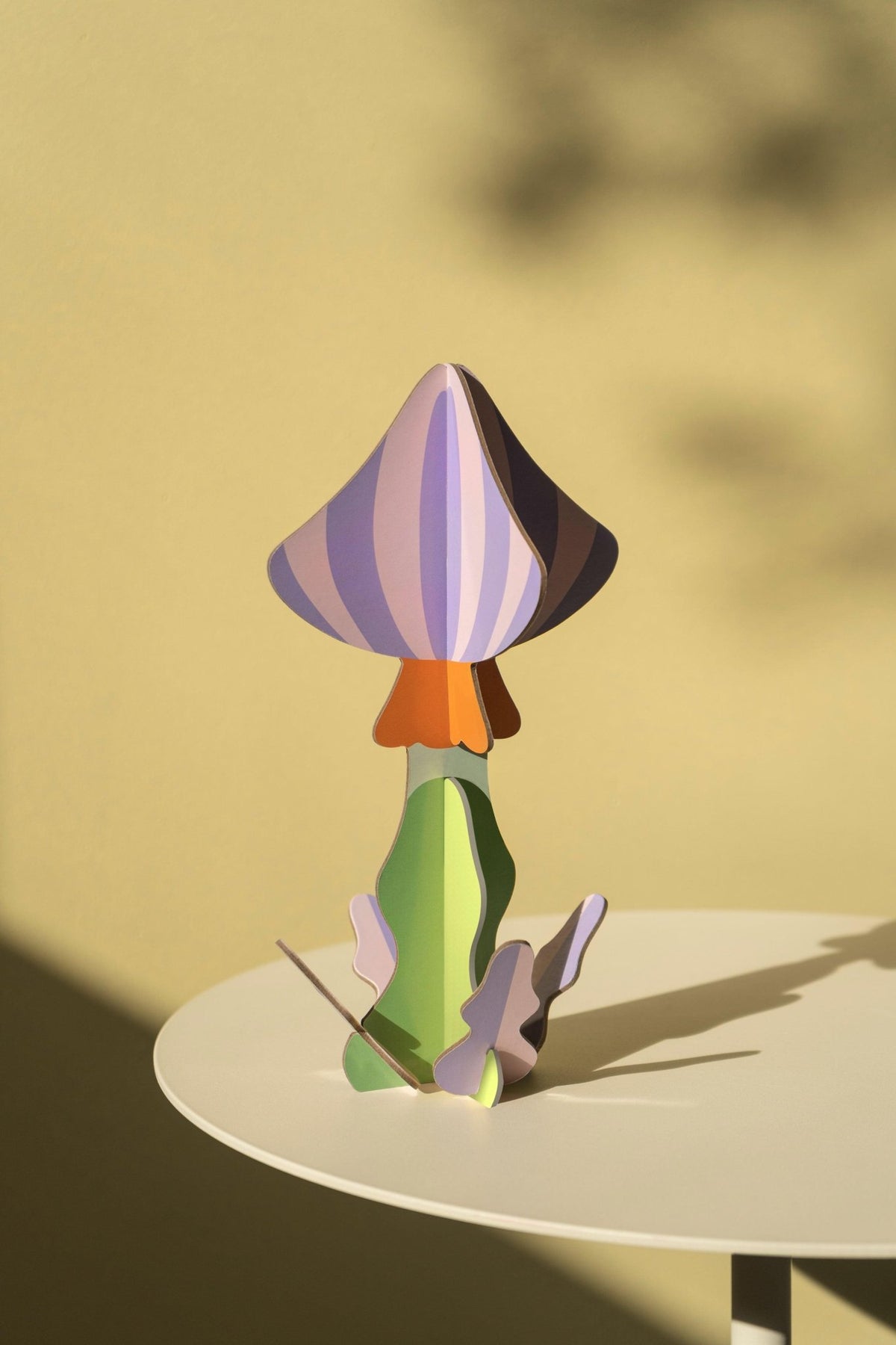 Octaevos Mushroom Paper Sculpture 2 adds unique pastel decor to a round dining table against a beige background.