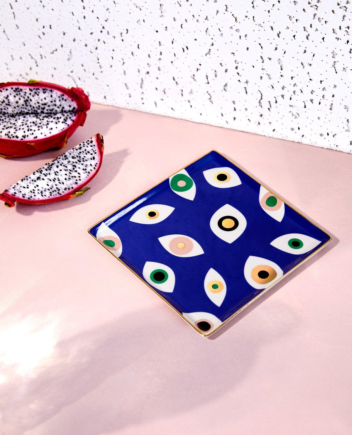 OCTAEVO Nazar Ceramic Tray—square blue ceramic with amulet eye pattern, shown next to dragon fruit.