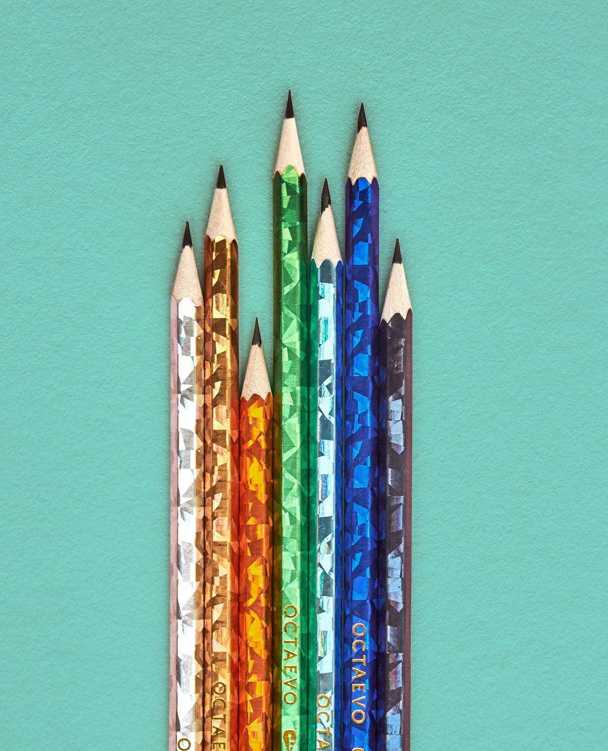 Six vibrant Octaevo NOMAD pencils arranged in a row on teal, each one eye-catching and colorful.