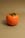 The Octaevo Persimmon Candle, with a green leafy top, makes stylish tabletop decor on any brown surface.