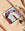 Purple Riviera Ceramic Tray by OCTAEVO with gemstones on a beige tablecloth and floral shadow. 