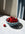 A blue Sicilia Ceramic Basket by OCTAEVO filled with cherries sits on a sunlit marble table, one cherry beside it.
