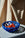 The Sicilia Ceramic Basket by OCTAEVO, filled with red tomatoes, stands on a round white table with beige fabric behind.