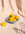 The light blue OCTAEVO Sicilia Ceramic Basket holds yellow plums on a beige cloth. 