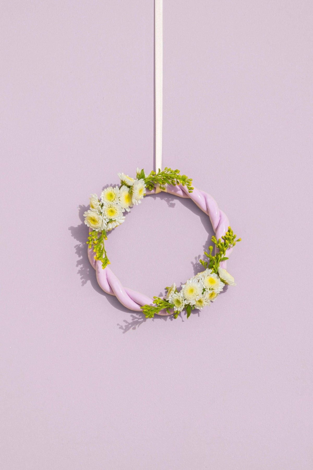 The purple OCTAEVO Sicilia Ceramic Trivet is displayed on a wall, adding a decorative pastel touch.