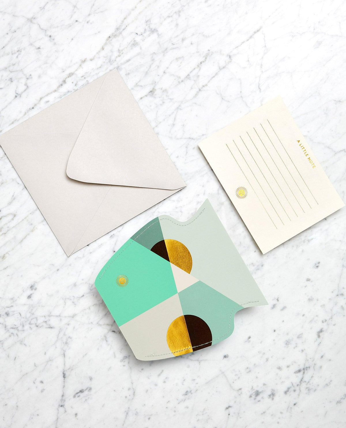 A mint Siena Mini Paper Vase by OCTAEVO with a greeting card, envelope, and lined notecard on white marble.