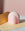 The Templo Candle by OCTAEVO, artisan-made and pink, sits on beige paper with a pastel pink background.