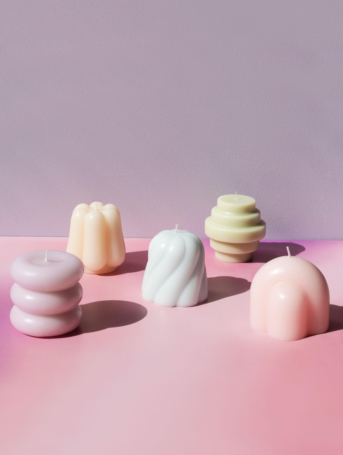 The OCTAEVO Templo Candle—Ivory, artisan-made with abstract shapes, shown on pink with a lavender backdrop.