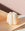 The Templo Candle by OCTAEVO—a white sculpted wax piece—rests on peach paper with a soft pink backdrop.