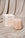 The Templo Candle by OCTAEVO sits beside its box on a beige satin fabric backdrop.