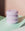 The OCTAEVO Templo Candle, a pastel purple three-tiered design, rests on mint and white with a pink backdrop.