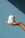 A hand holds the Templo Candle by Octaevo—a white, twisted artisan piece—against a blue background with diagonal shadow.