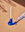 A hand holds the OCTAEVO Templo Candle Holder in blue with a white candle against a peach background.