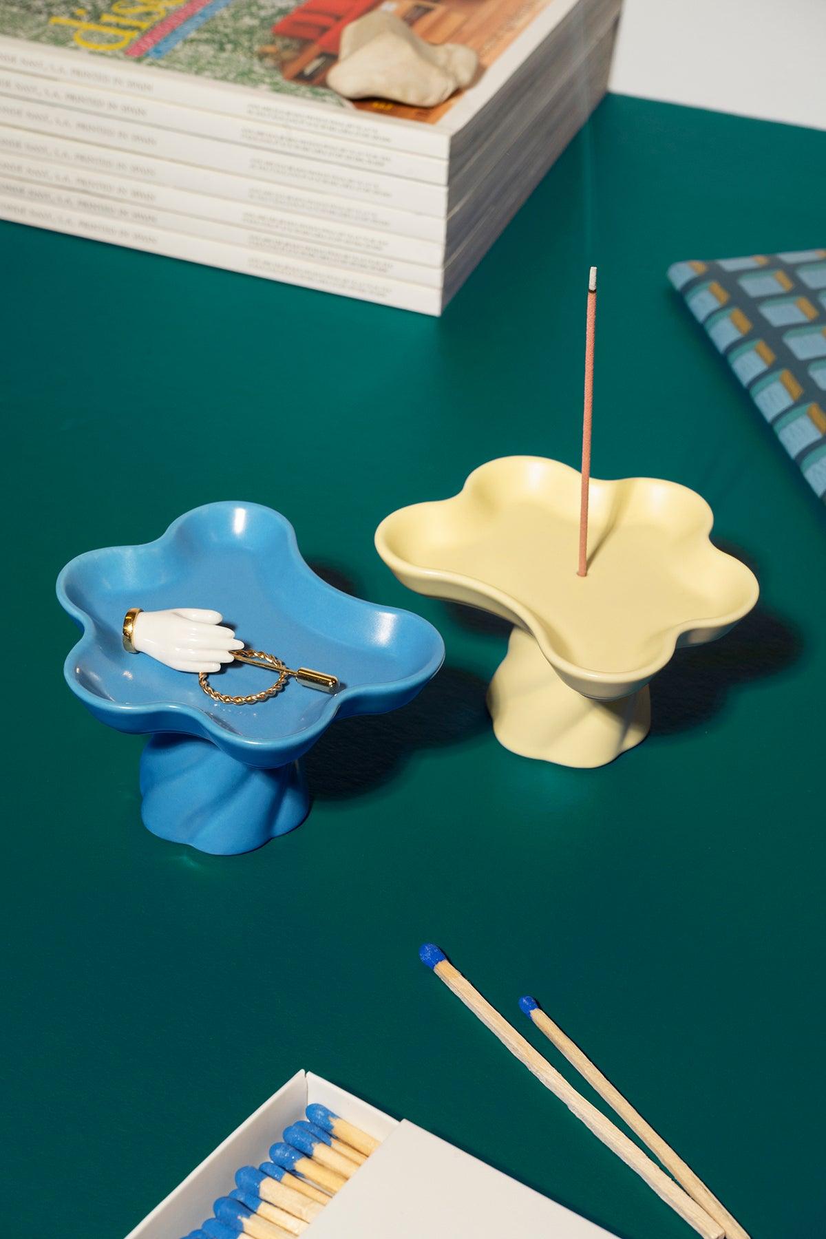 The Octaevo Templo Incense Holder in yellow doubles as a decorative flower-shaped tray and incense holder on a green table.