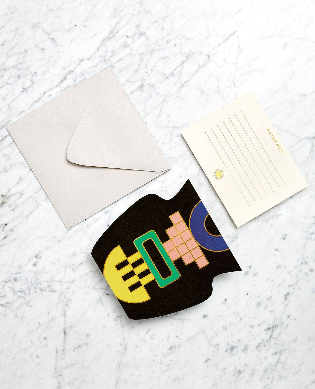 A blank envelope, a lined notecard, and a black OCTAEVO Templo Mini Paper Vase card on white marble.