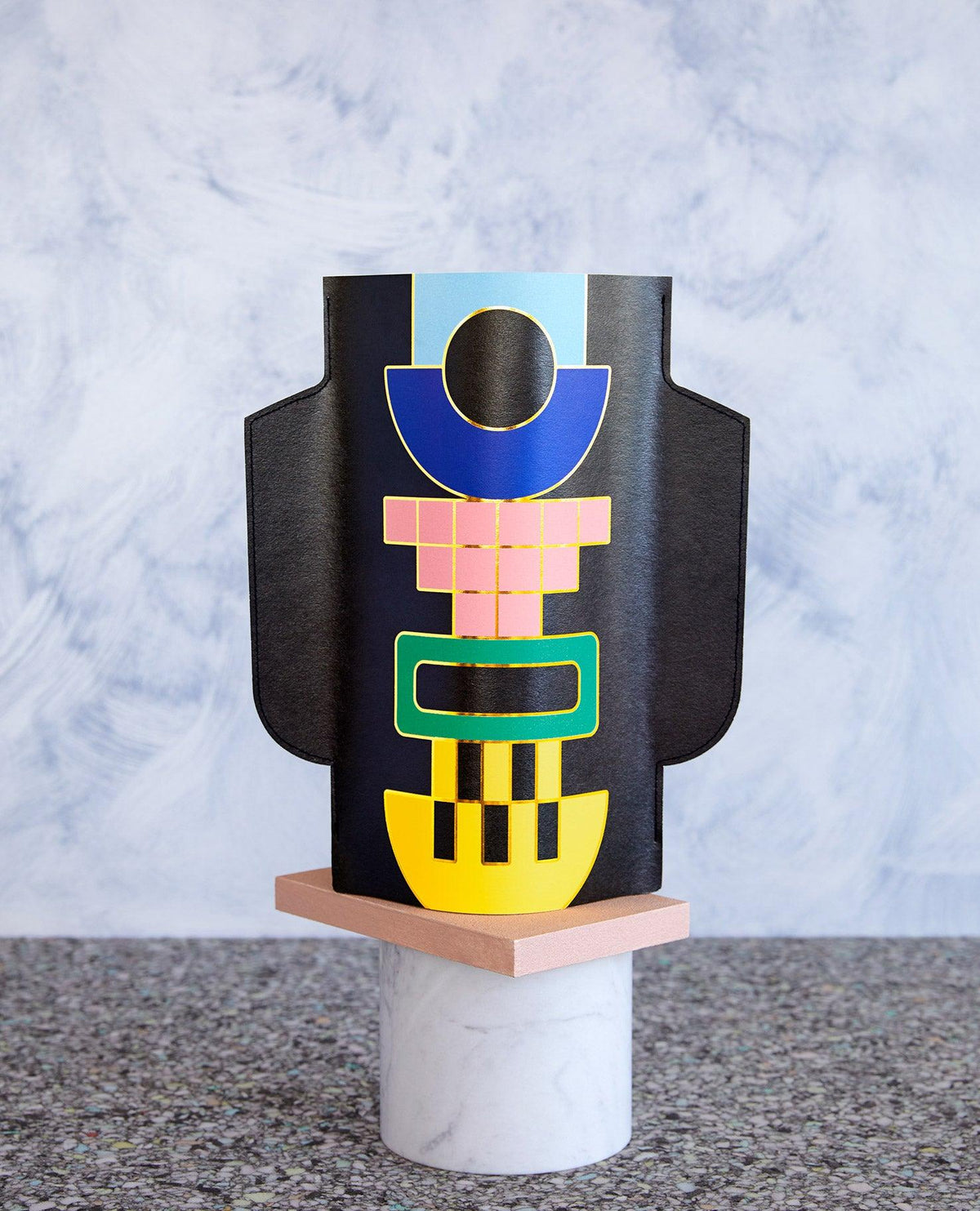 The Templo Paper Vase in black by OCTAEVO is a colorful abstract piece, handcrafted and displayed on a marble and wood base.