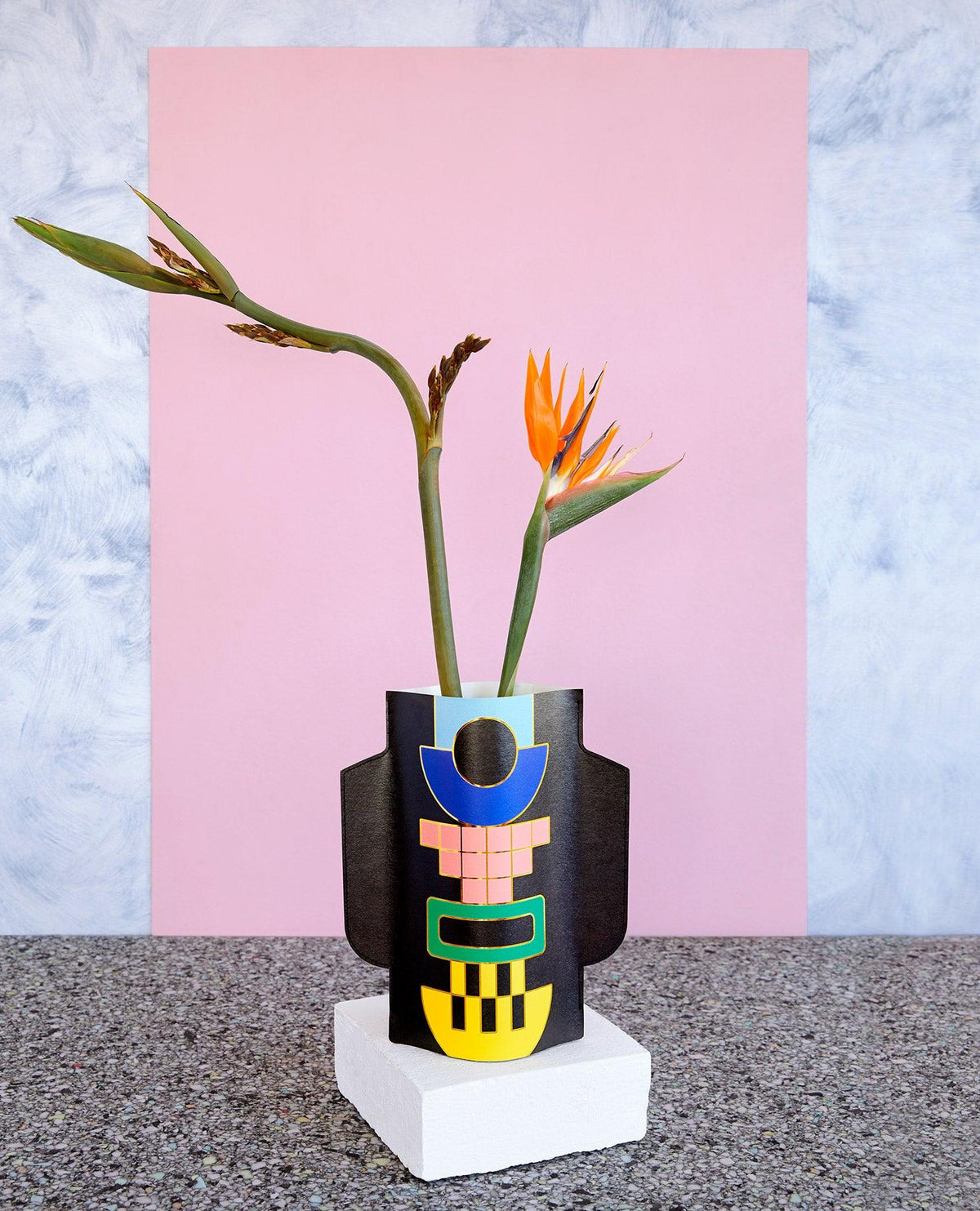 The OCTAEVO Templo Paper Vase in black features bird of paradise blooms with pink and marble-textured backgrounds.