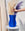 A hand arranges pampas grass in the OCTAEVO Venus Paper Vase, shaped like a blue female torso, on a round table.